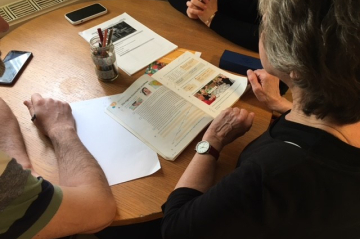 3 Personen sitzen am Tisch und lernen aus einem Buch